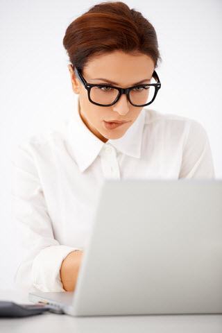 Woman biting lip while working on laptop