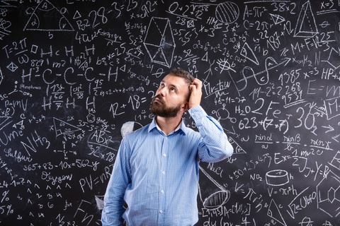 Man Scratching Head In Front of Chalk board with formulas