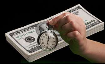 Hand holding stop watch over stack of money